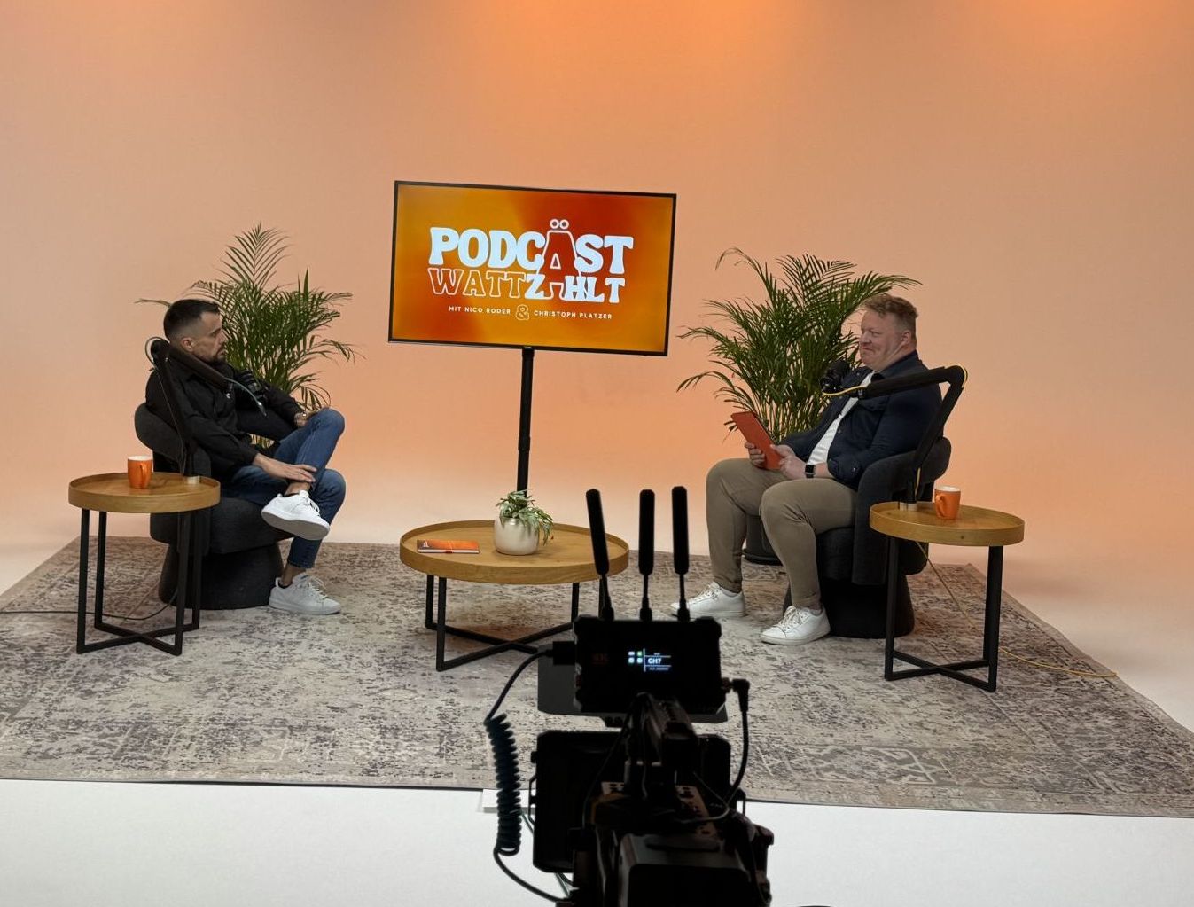 Zwei Männer sitzen im Podcaststudio und nehmen eine Folge auf
